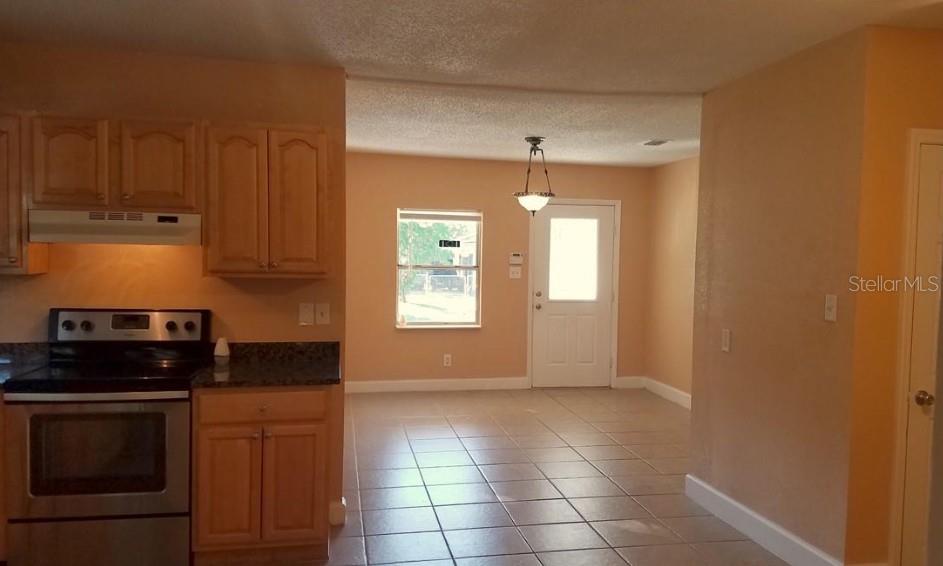 A kitchen with light wood cabinets and tile flooring opens into a dining area — 2921 W WALNUT STREET, TAMPA, FL