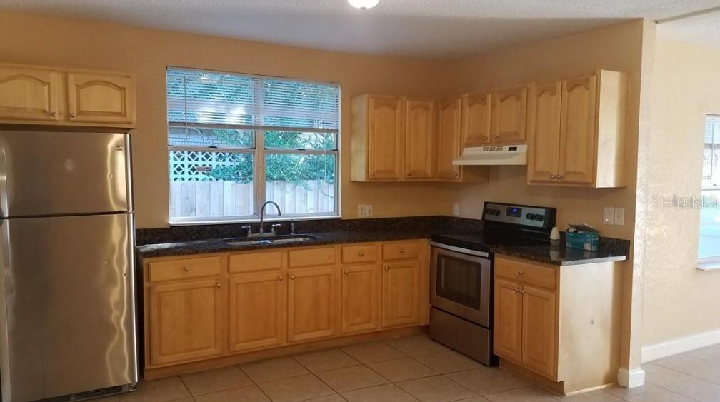 A kitchen with light wood cabinets, stainless steel appliances, and dark granite countertops — 2921 W WALNUT STREET, TAMPA, FL