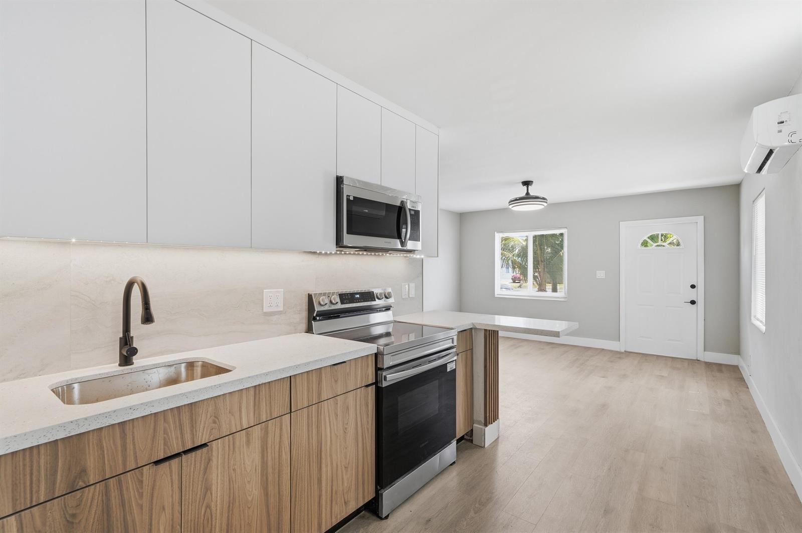 A modern kitchen features wood-grain lower cabinets, white upper cabinets, and a stainless steel stove — 2625 NW 10th Street, Pompano Beach FL 33069, POMPANO BEACH, FL