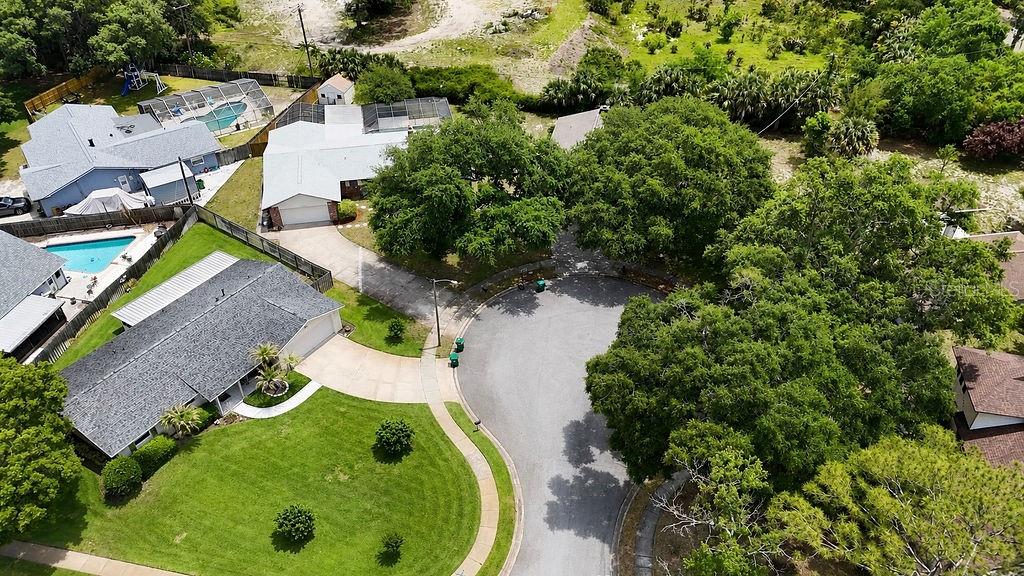 An aerial view shows a suburban cul-de-sac with houses, swimming pools, and large shade trees — 3033 DEVON COURT, TITUSVILLE, FL