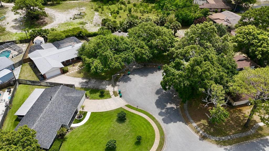 An aerial view shows a suburban cul-de-sac with houses, driveways, and mature trees — 3033 DEVON COURT, TITUSVILLE, FL