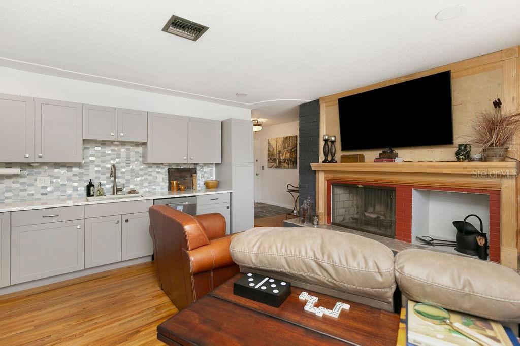 A living room features a fireplace with a mounted television, a kitchenette, and hardwood floors — 3033 DEVON COURT, TITUSVILLE, FL