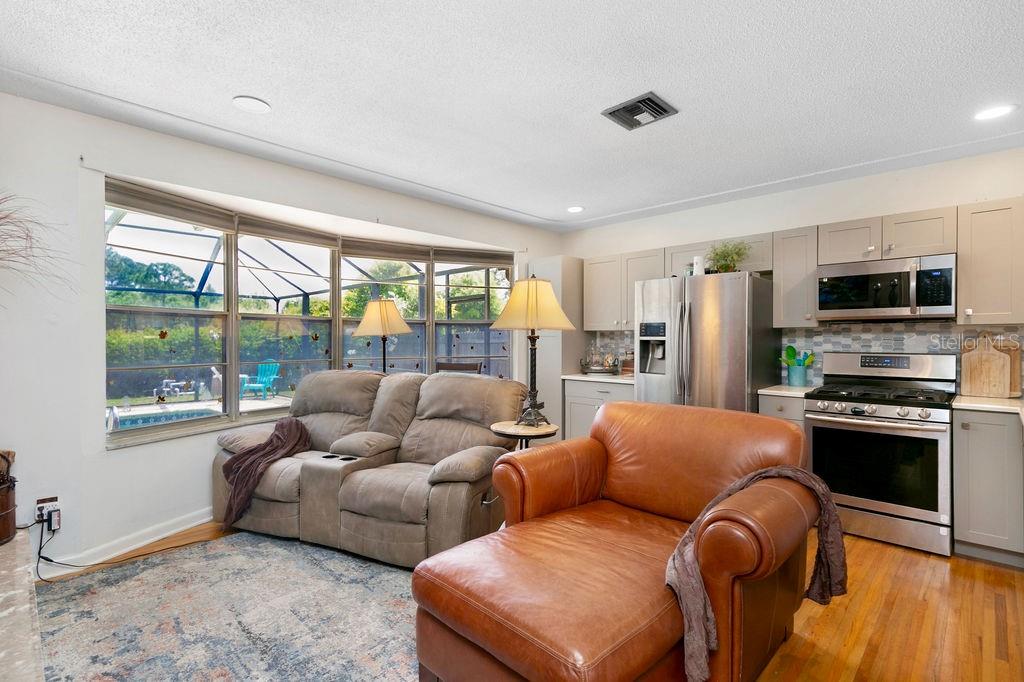 A living room with a leather chaise lounge and sofa sits adjacent to a kitchen — 3033 DEVON COURT, TITUSVILLE, FL