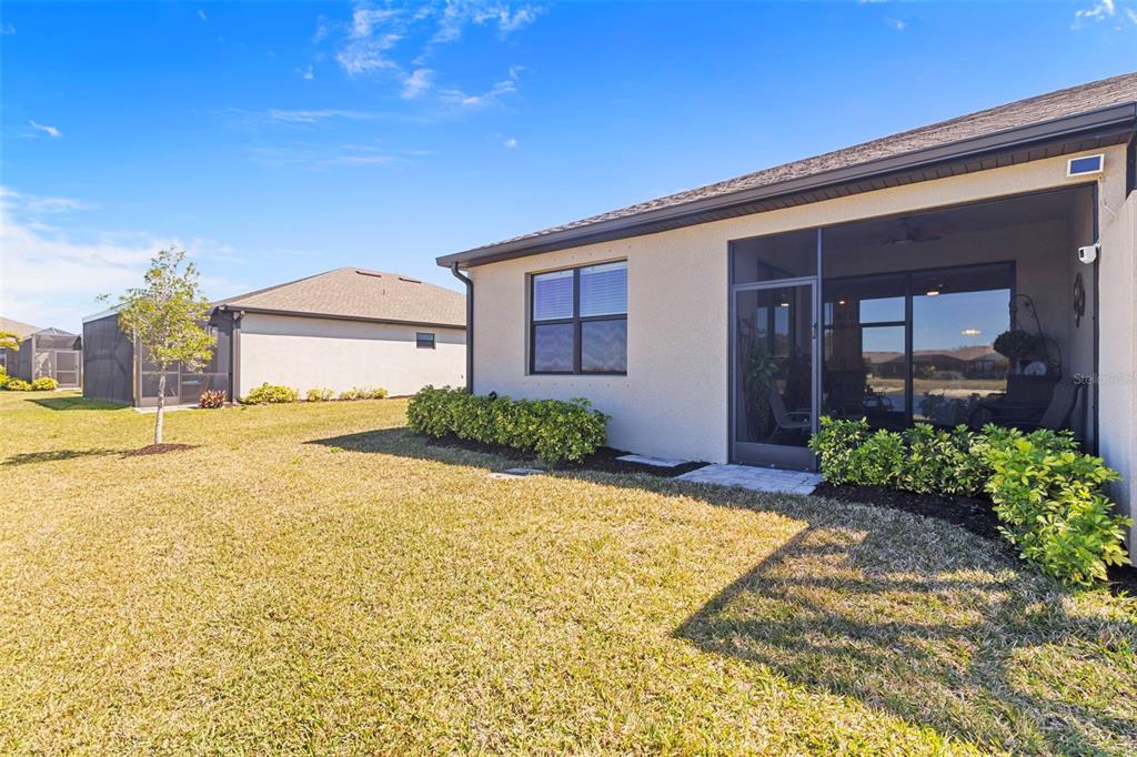 The exterior of a house features a screened-in patio, a grassy yard, and a window — 2145 BONITO WAY, PORT CHARLOTTE, FL