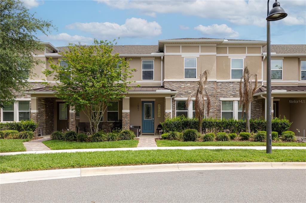 A two-story townhouse exterior features a blue front door, stone accents, and a paved walkway — 16461 PRAIRIE SCHOOL DRIVE, WINTER GARDEN, FL