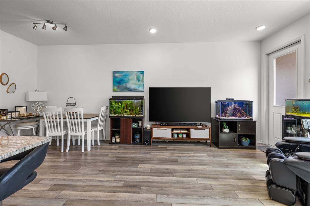 An open-concept living room and kitchen feature white cabinetry, light wood flooring, and cream furniture — 16461 PRAIRIE SCHOOL DRIVE, WINTER GARDEN, FL