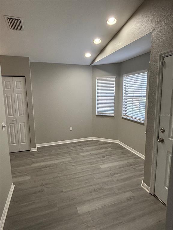 An empty room features gray wood-look flooring, light gray walls, recessed lighting, and two windows — 3906 NE 22ND STREET, OCALA, FL
