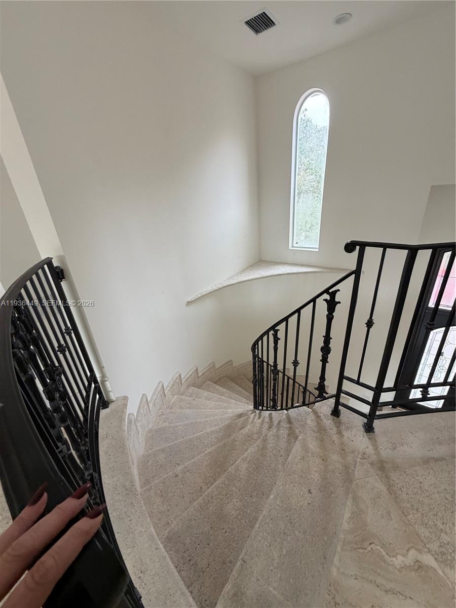 A curved stone staircase features black metal railings and a tall arched window — 673 Destacada Ave, Coral Gables FL 33156, CORAL GABLES, FL