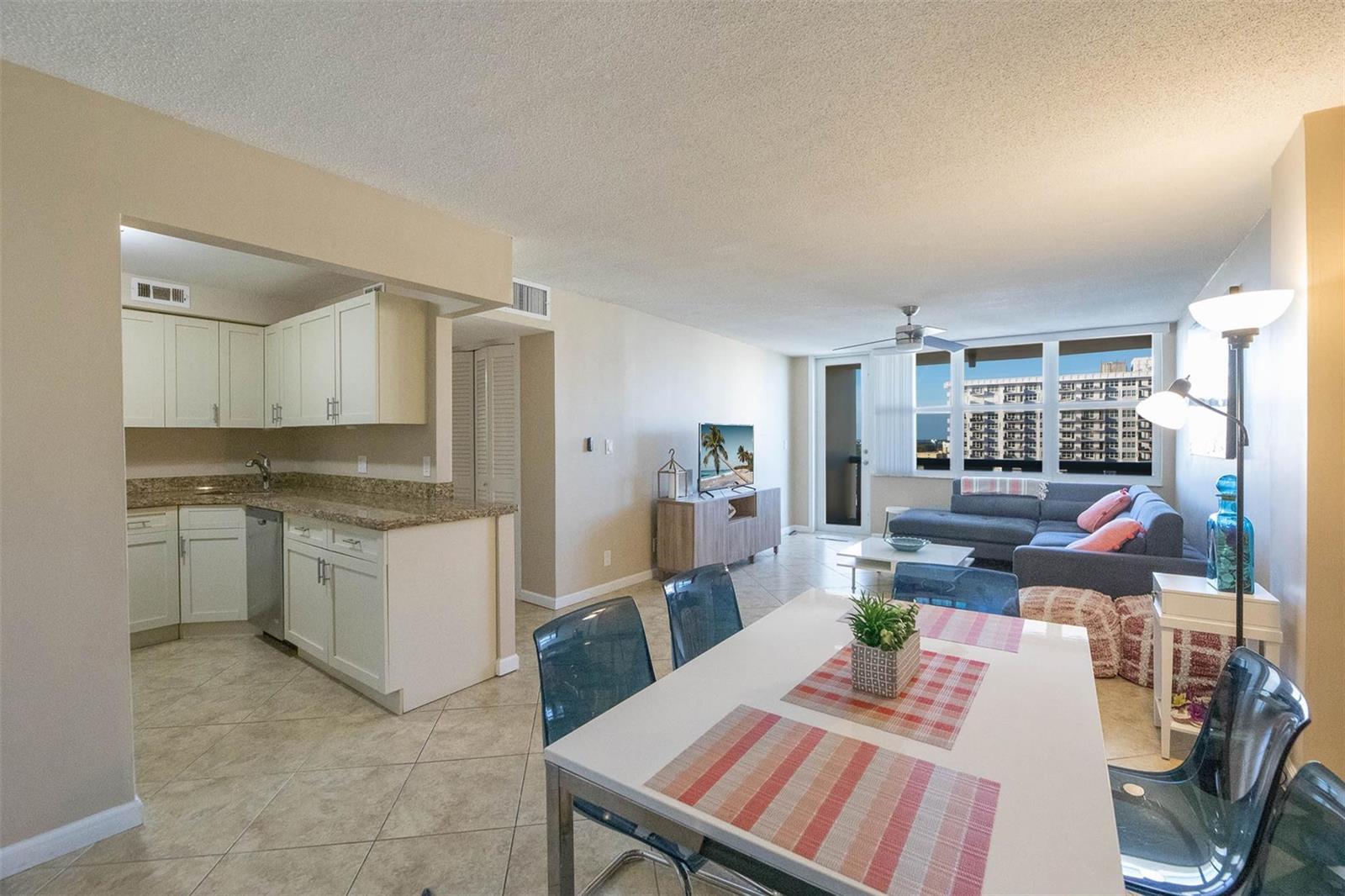 An open-concept living and dining area features a kitchen with white cabinets and tile floors — 305 N Pompano Beach Boulevard # 1403, Pompano Beach FL 33062, POMPANO BEACH, FL