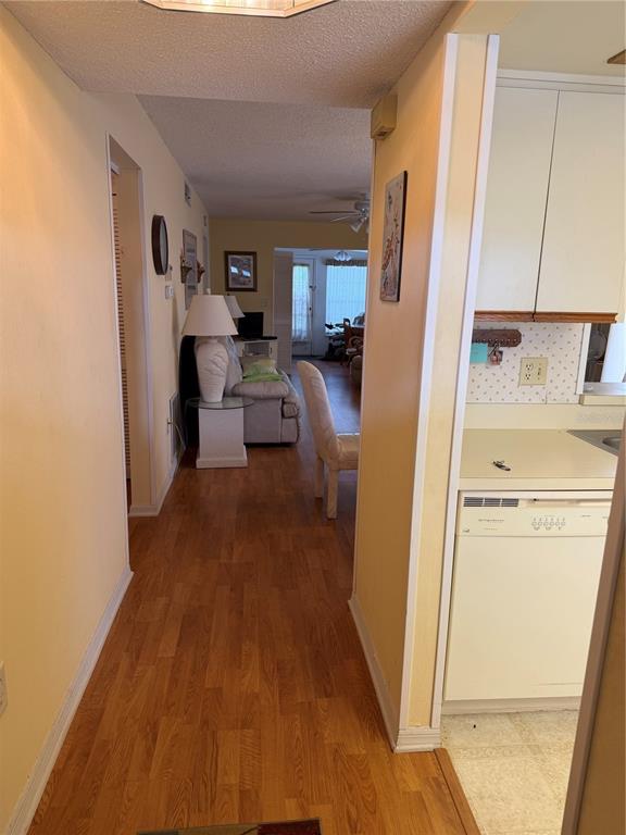 A hallway leads from a kitchen with a white dishwasher toward a living room area — 2400 WINDING CREEK BOULEVARD UNIT 18A-110, CLEARWATER, FL