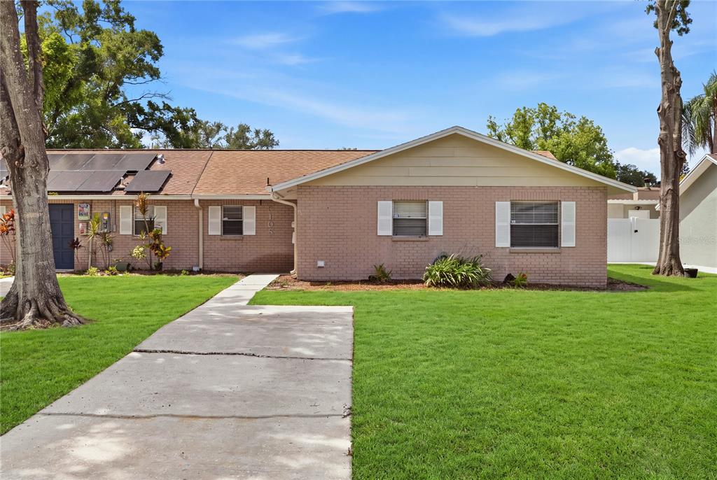 A single-story brick house with a concrete walkway, solar panels, and a green lawn — 5108 LAWNTON COURT, TAMPA, FL