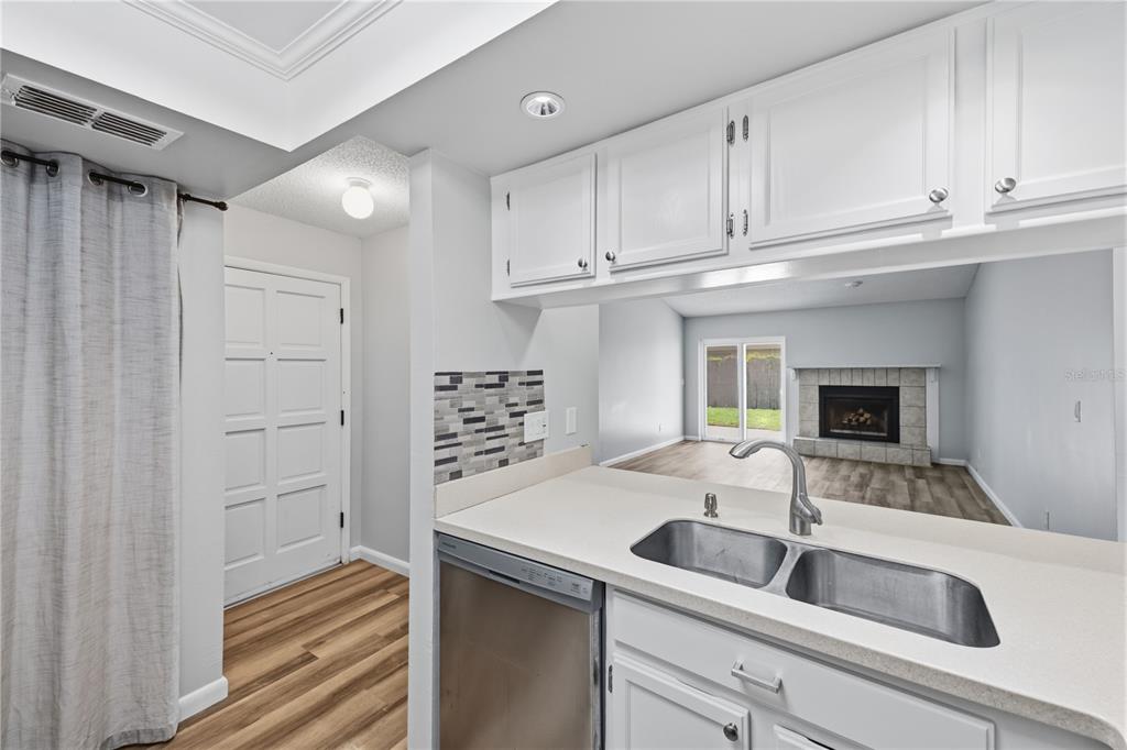 A kitchen sink and dishwasher overlook a living room with a fireplace and sliding doors — 5108 LAWNTON COURT, TAMPA, FL