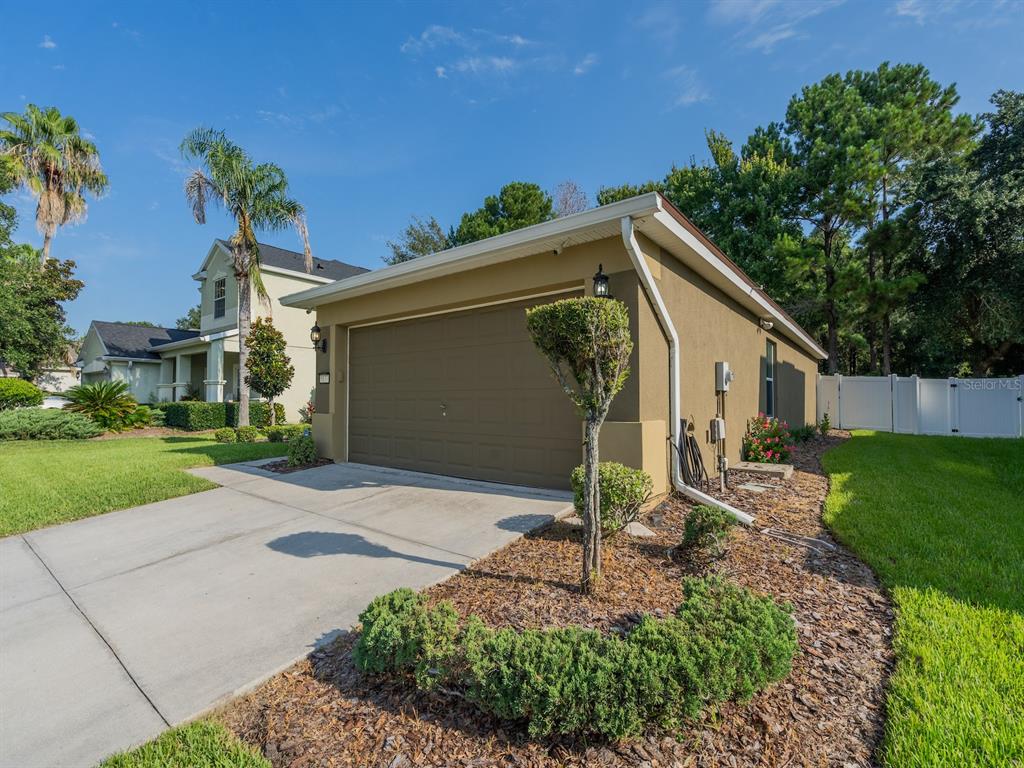 A tan detached garage with a brown door sits on a concrete driveway near trees — 5177 SW 39TH STREET, OCALA, FL
