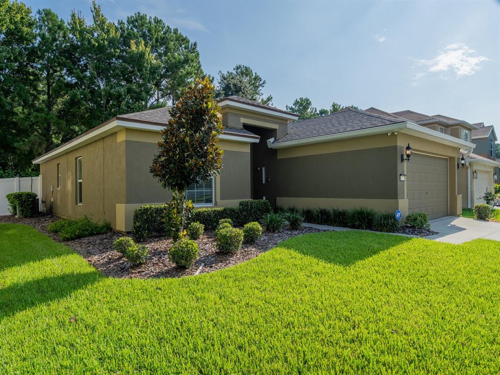 A single-story house with a two-car garage, tan stucco exterior, and a landscaped front yard — 5177 SW 39TH STREET, OCALA, FL