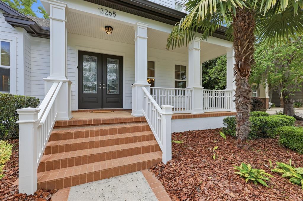 A two-story white house with a front porch, palm tree, and manicured landscaping — 13265 SW 6TH AVENUE, NEWBERRY, FL