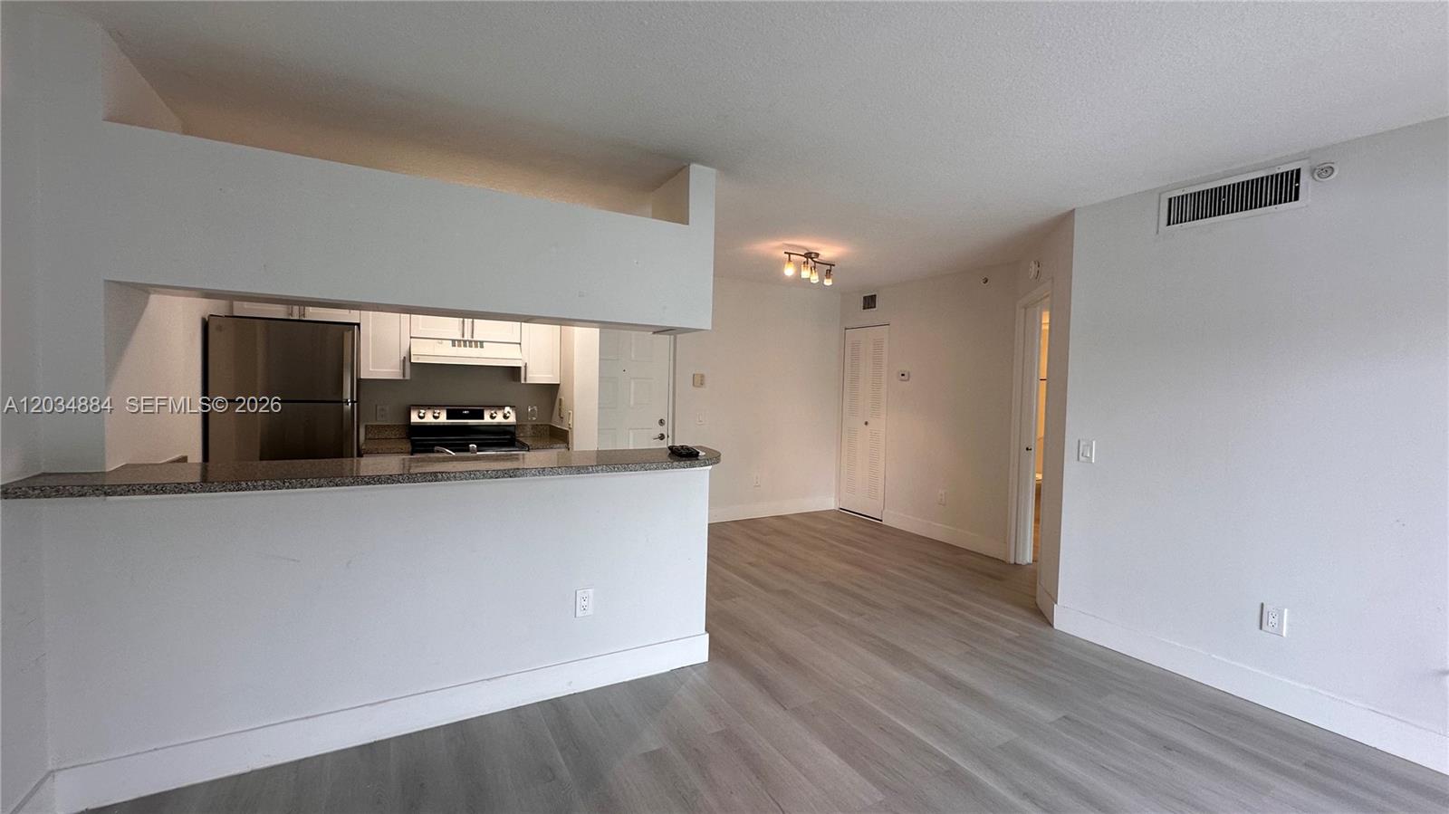 A kitchen with stainless steel appliances overlooks an open living area with light flooring — HOLLYWOOD, FL
