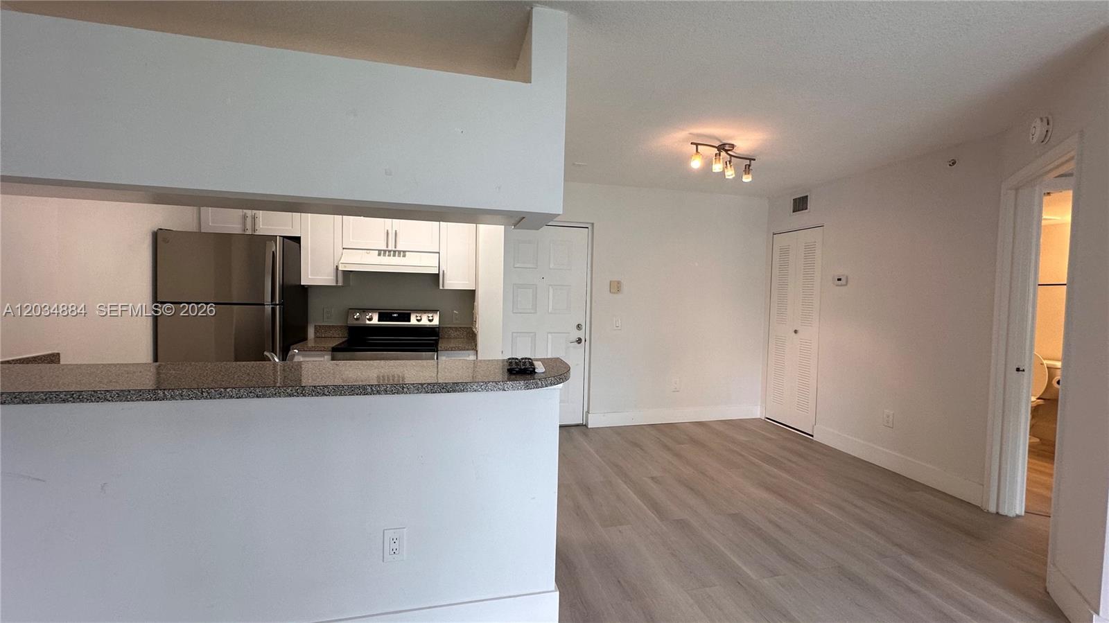A kitchen with stainless steel appliances and a breakfast bar opens to a living area — HOLLYWOOD, FL
