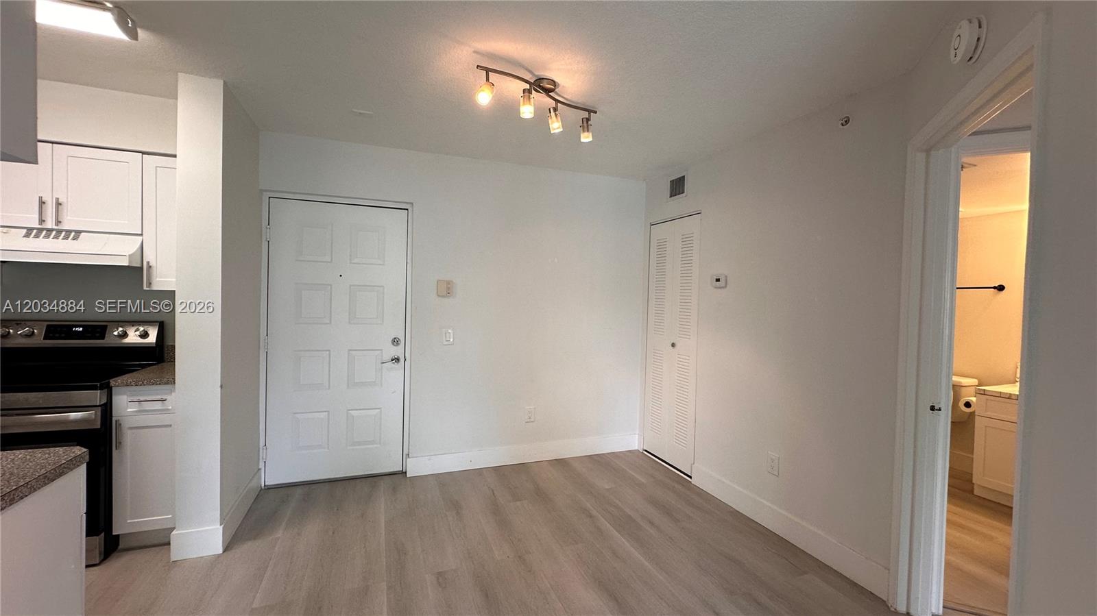 An interior view shows a kitchen area with light wood floors and a white door — HOLLYWOOD, FL