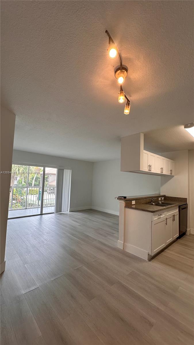 An open-concept living area features light wood-look flooring, a kitchen peninsula, and a sliding door — HOLLYWOOD, FL