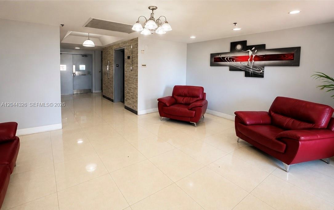 A lobby features light tile flooring, red leather armchairs, and a modern wall art piece — 1825 W 44th Pl # 806, Hialeah FL 33012, HIALEAH, FL
