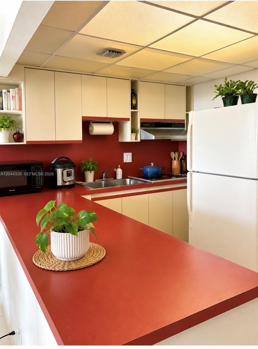 A kitchen features red countertops, cream-colored cabinets, and a drop ceiling with recessed lighting — 1825 W 44th Pl # 806, Hialeah FL 33012, HIALEAH, FL