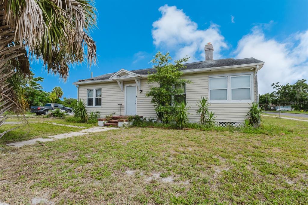 A single-story house with light-colored siding, a front porch, and a chimney under a blue sky — 2560 5TH AVENUE S, ST PETERSBURG, FL