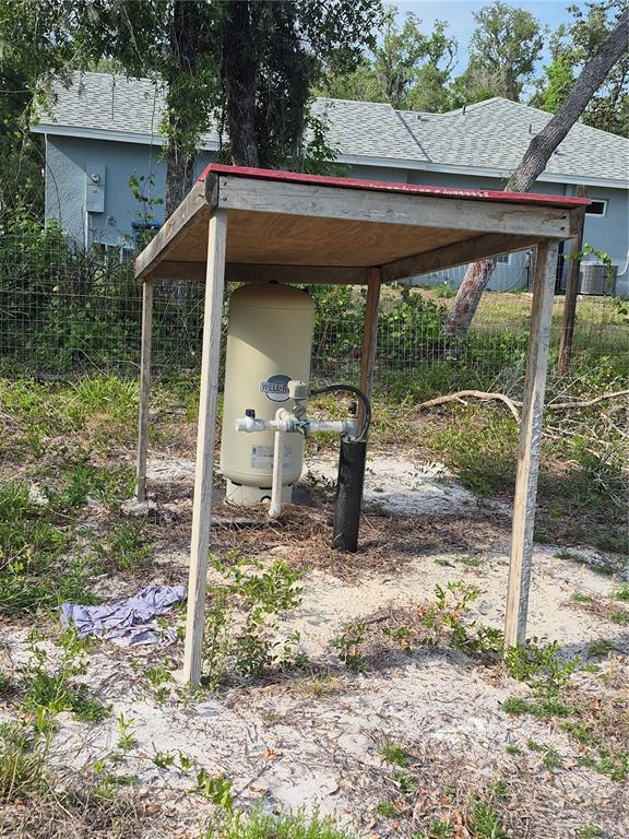 A well pressure tank stands under a simple wooden shelter in a sandy yard — 7490 SHASTA STREET, WEBSTER, FL
