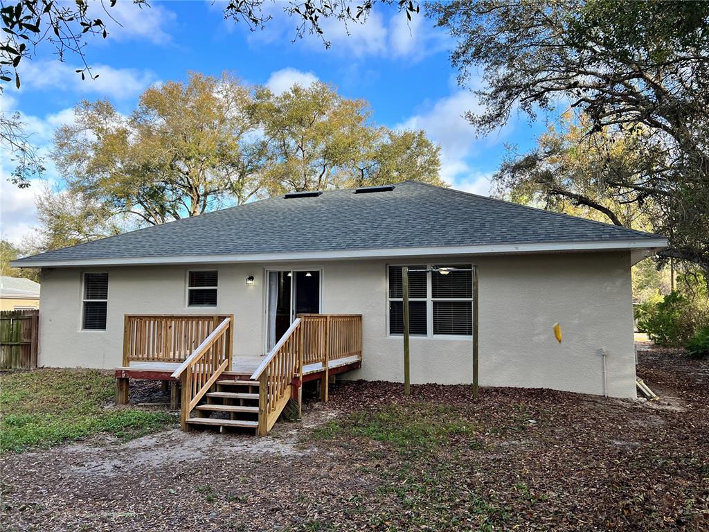 The exterior of a single-story house features a wooden deck with stairs and a yard — 2336 W ORANGE ROAD, DELAND, FL