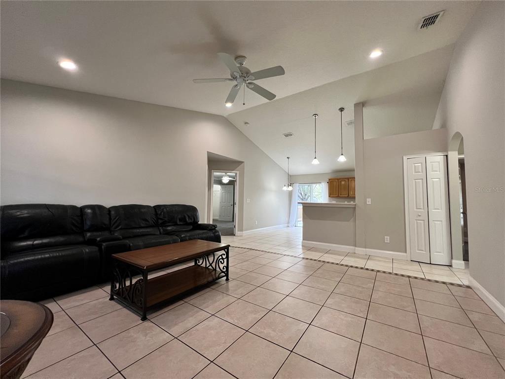 A living room with tile flooring, a black leather sofa, and a vaulted ceiling — 2336 W ORANGE ROAD, DELAND, FL