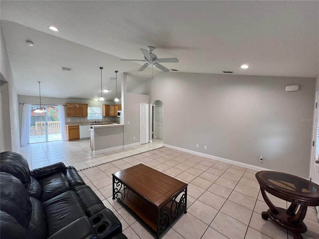 A living room with tile flooring, a ceiling fan, and an open kitchen in the background — 2336 W ORANGE ROAD, DELAND, FL