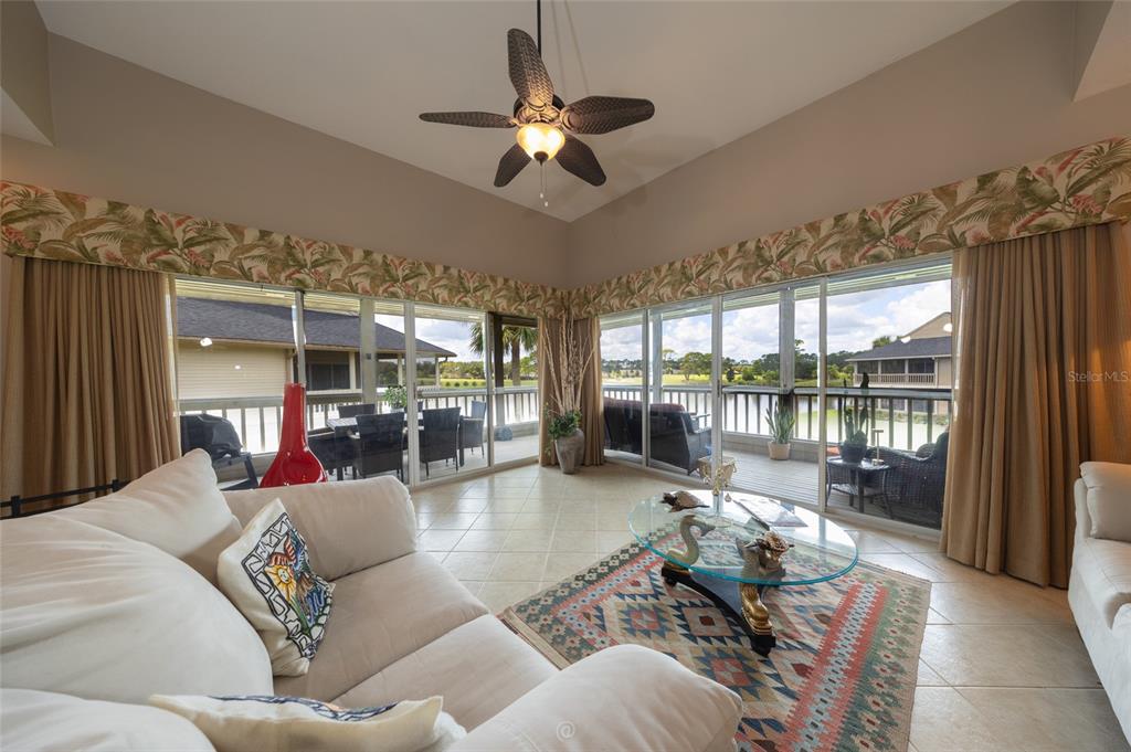 A living room with tile floors, a ceiling fan, and sliding glass doors overlooking a patio — 11 MAGNOLIA DRIVE S UNIT 11, ORMOND BEACH, FL