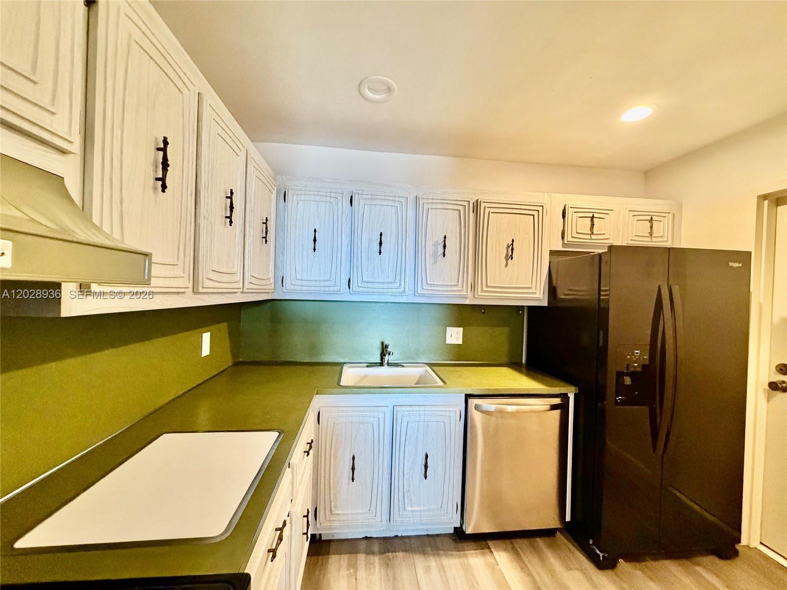A kitchen features white wood-grain cabinets, green countertops, a black refrigerator, and marble-patterned flooring — 2101 S Ocean Dr # 306, Hollywood FL 33019, HOLLYWOOD, FL