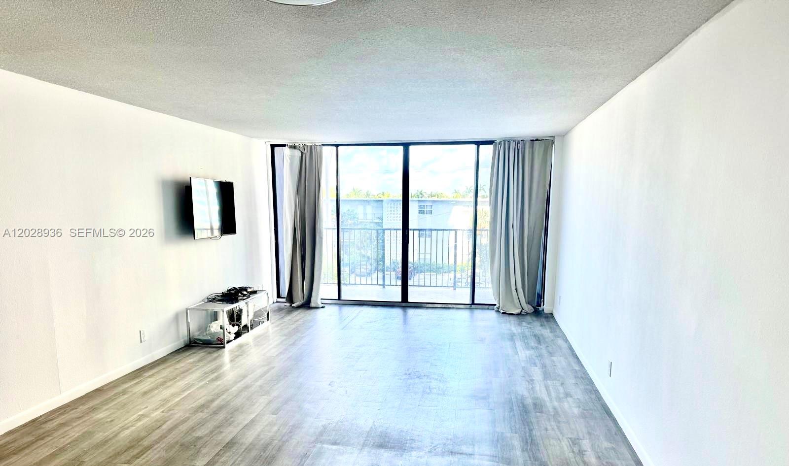 An empty room features white walls, marble-patterned tile flooring, and a sliding glass door — 2101 S Ocean Dr # 306, Hollywood FL 33019, HOLLYWOOD, FL