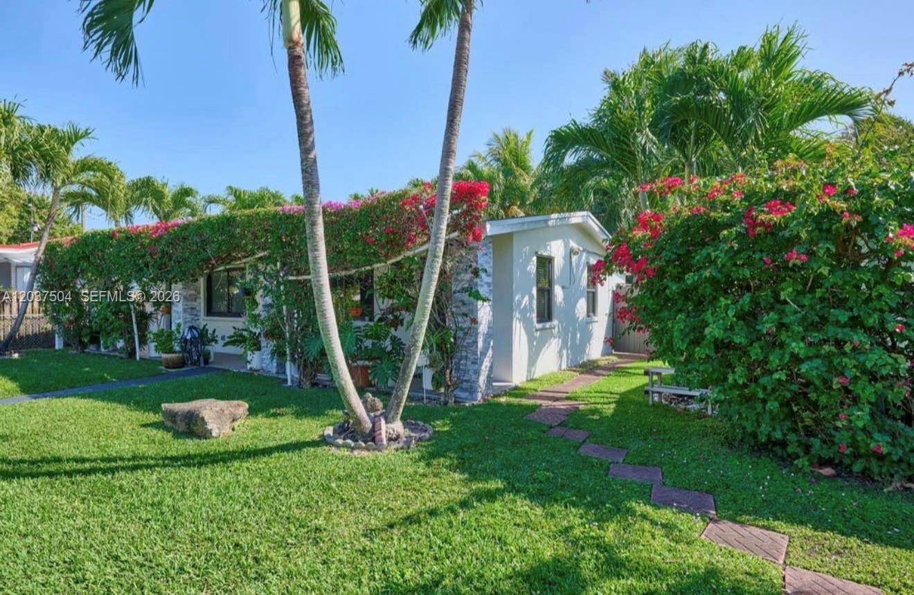 A single-story house with a bougainvillea-covered facade and a stone walkway in the yard — 612 W Drew St, Lantana FL 33462, LANTANA, FL