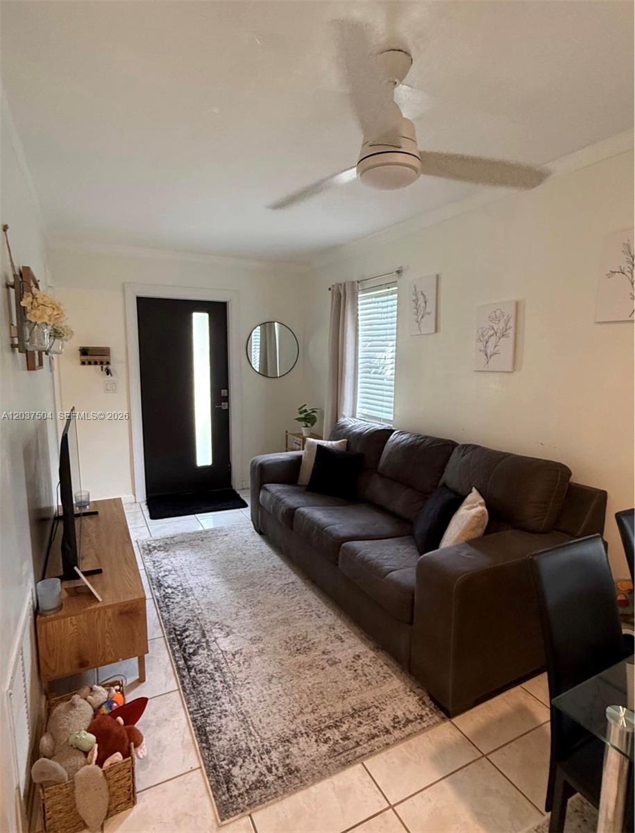 A living room features a dark sofa, a patterned area rug, and a ceiling fan — 612 W Drew St, Lantana FL 33462, LANTANA, FL