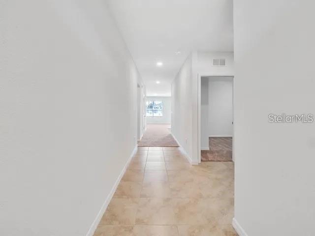 A tiled hallway leads to a carpeted room with a window at the end — 603 MUSKRAT DRIVE, KISSIMMEE, FL