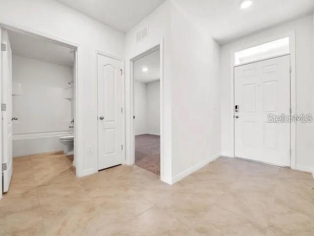 A tiled entryway features a front door, a bathroom doorway, and a hallway leading inside — 603 MUSKRAT DRIVE, KISSIMMEE, FL