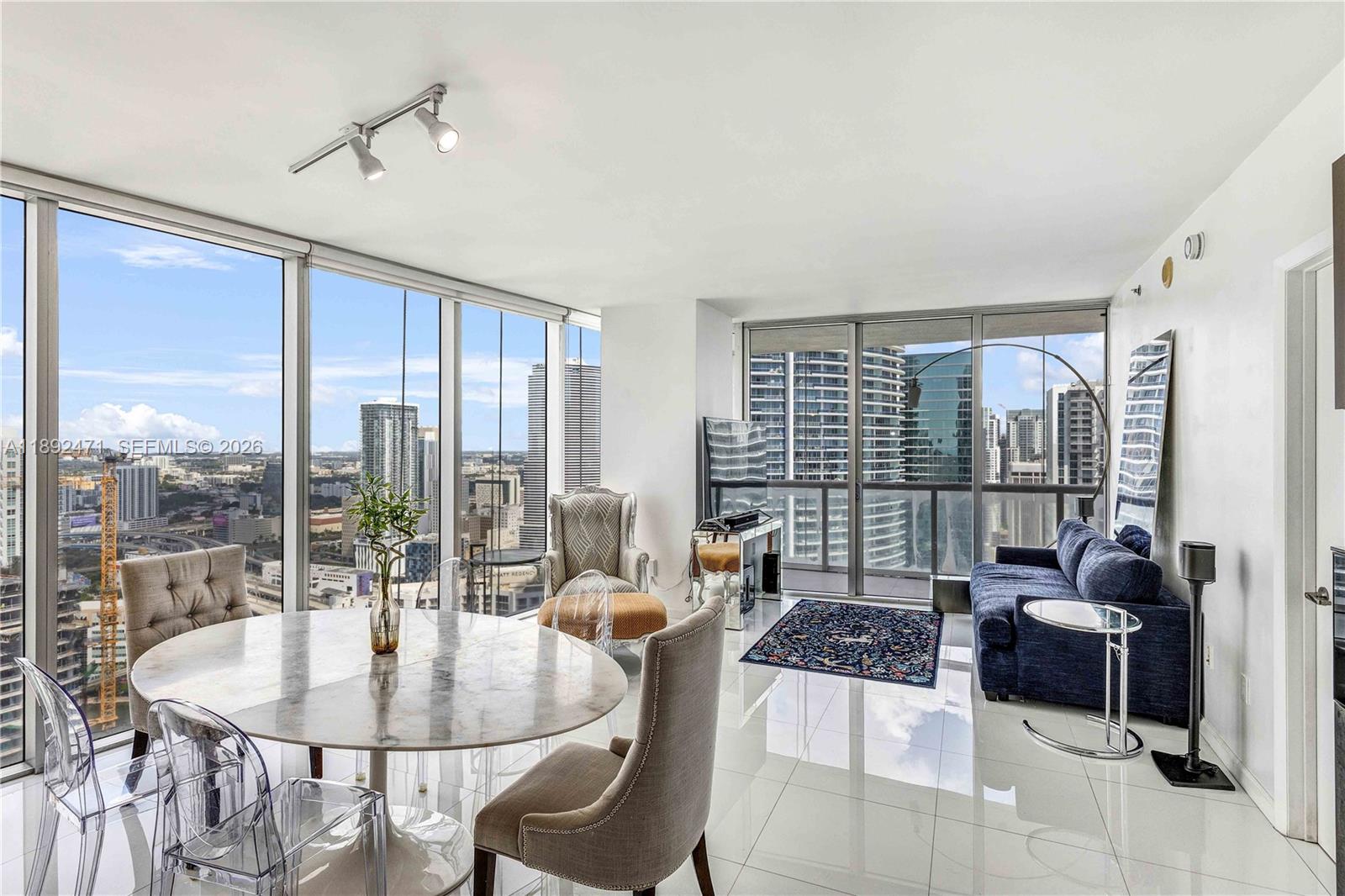 A modern high-rise apartment living and dining area features floor-to-ceiling windows with city views — 475 Brickell Ave # 4015, Miami FL 33131, MIAMI, FL