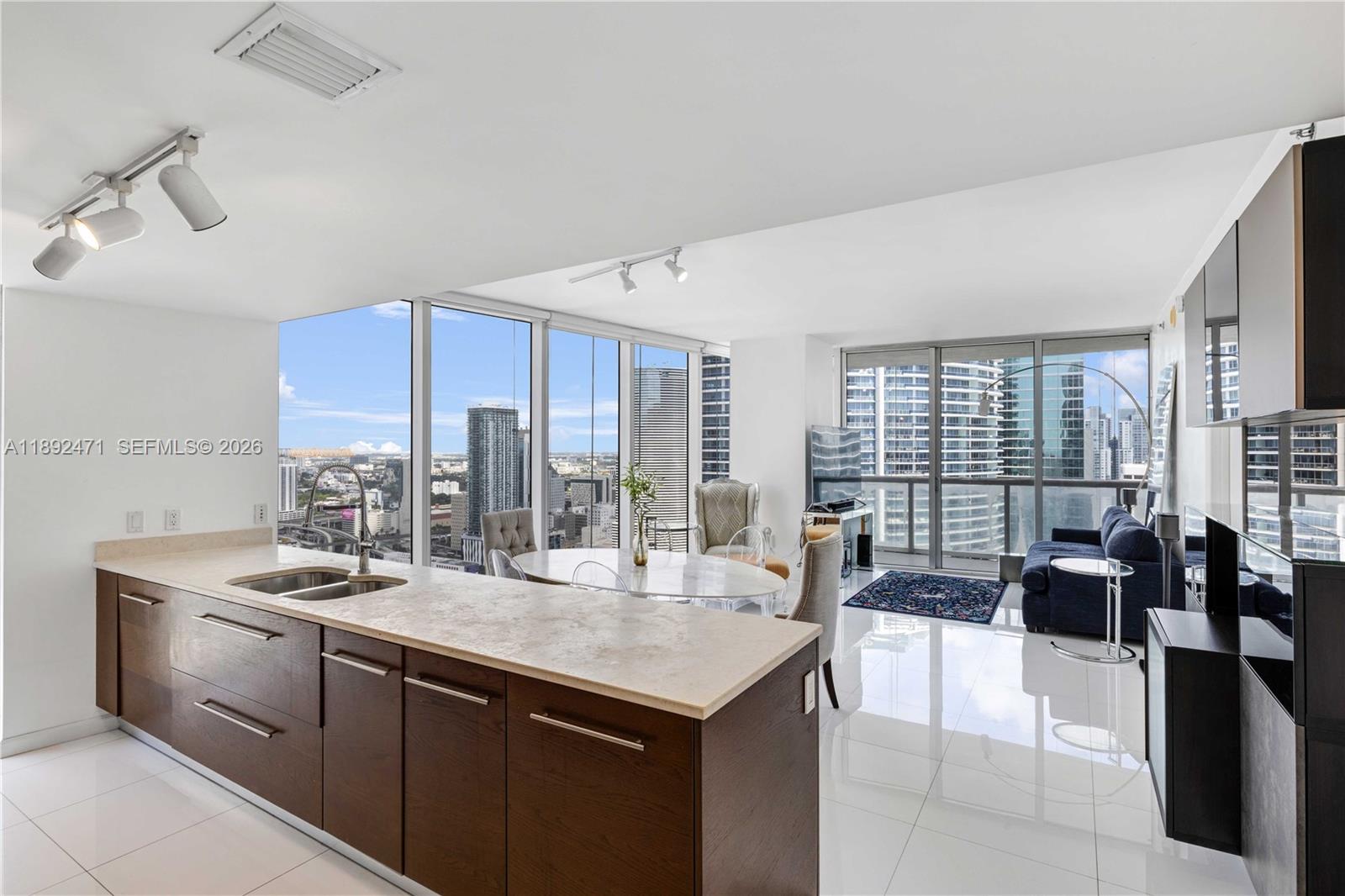 A modern open-concept kitchen and living area with floor-to-ceiling windows and city views — 475 Brickell Ave # 4015, Miami FL 33131, MIAMI, FL