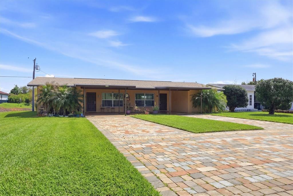 A single-story house with a paved driveway and a covered front porch under a blue sky — 12125 MARGARITA AVENUE, NORTH PORT, FL