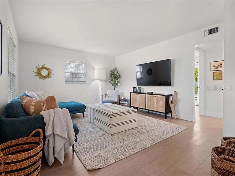 A living room features a blue sectional sofa, a striped ottoman, and a wall-mounted television — 8067 123RD STREET, SEMINOLE, FL