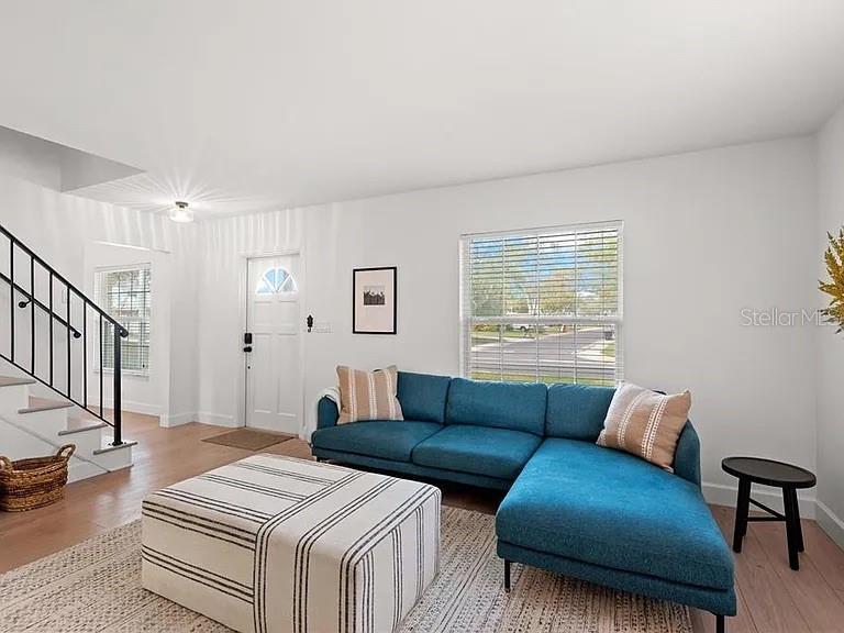 A living room features a blue sectional sofa, a striped ottoman, and a staircase — 8067 123RD STREET, SEMINOLE, FL