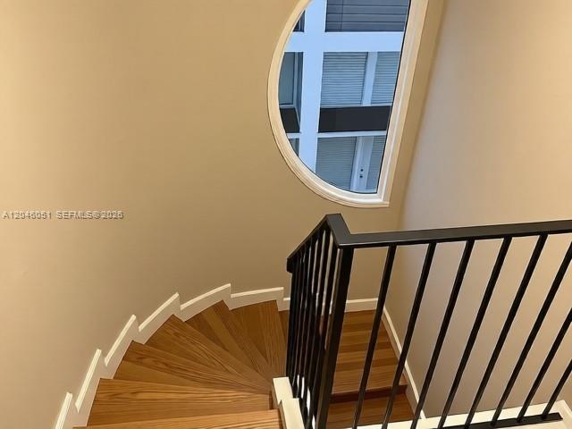 A wooden spiral staircase features a black metal railing and a large arched window — TALLAHASSEE, FL