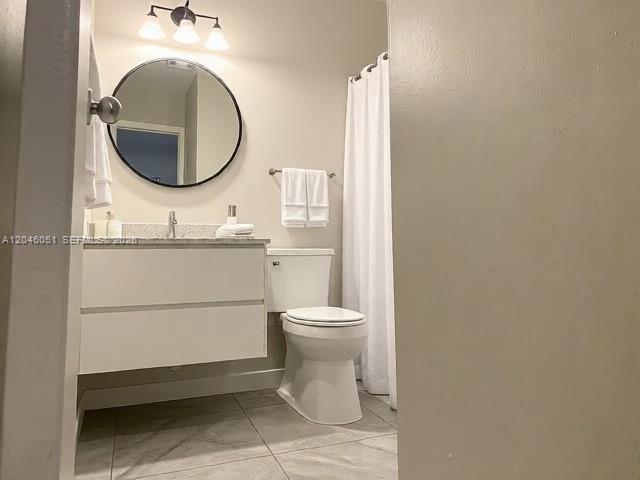 A bathroom features a floating vanity, round mirror, white toilet, and a shower with a curtain — TALLAHASSEE, FL