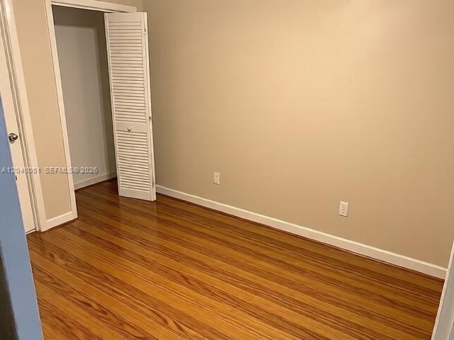 An empty room features light-colored walls, wood-look flooring, and a white louvered closet door — TALLAHASSEE, FL