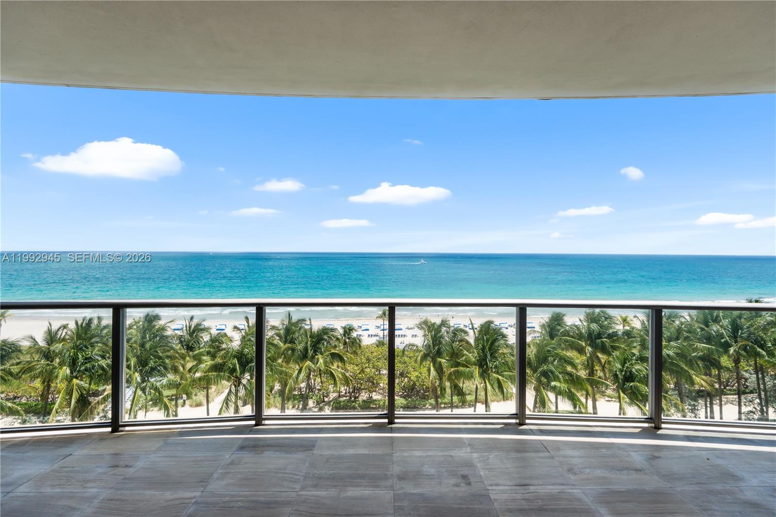 A balcony with tile flooring overlooks a beach, palm trees, and the ocean — 9703 Collins Ave # 600, Bal Harbour FL 33154, BAL HARBOUR, FL