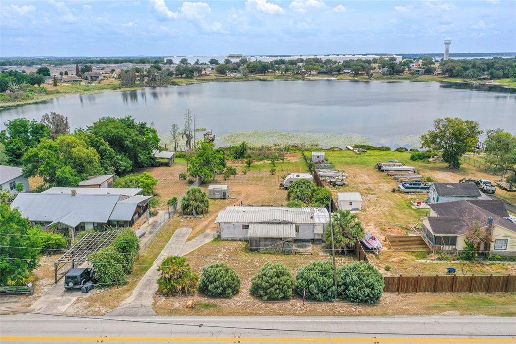 An aerial view shows a lakefront property with several houses, outbuildings, and parked boats — 4880 OLD LUCERNE PARK ROAD, WINTER HAVEN, FL