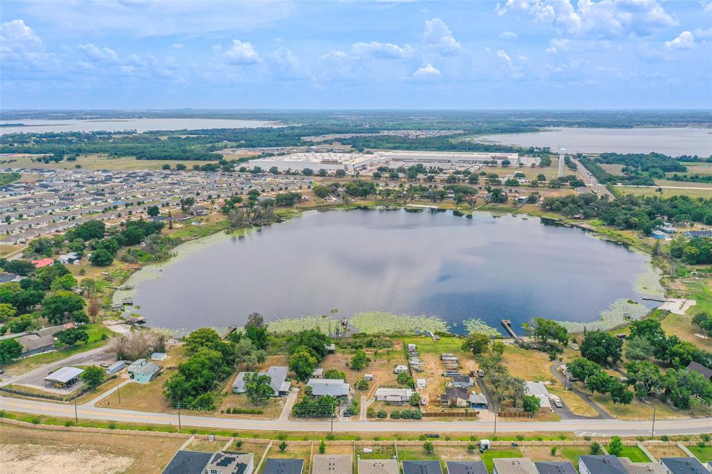 An aerial view shows a large lake surrounded by residential neighborhoods and a warehouse complex — 4880 OLD LUCERNE PARK ROAD, WINTER HAVEN, FL