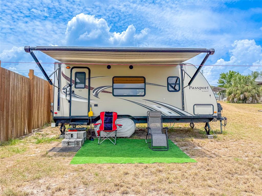 A tan Passport travel trailer with an extended awning sits on a patch of artificial turf — 4880 OLD LUCERNE PARK ROAD, WINTER HAVEN, FL