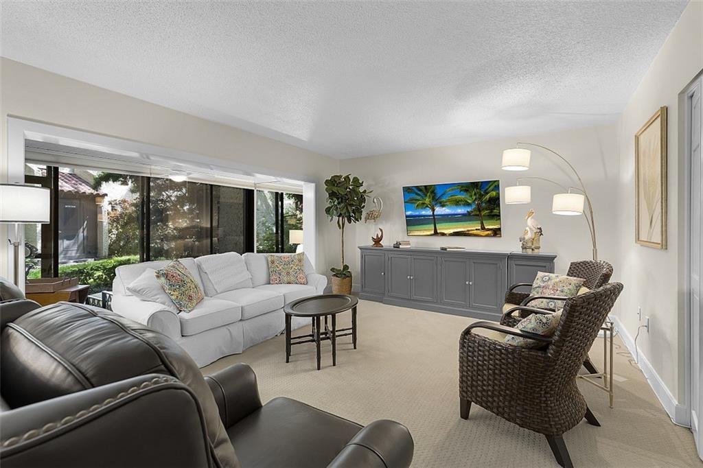 A living room features a white sofa, wicker chairs, a gray console, and large windows — INDIAN RIVER SHORES, FL